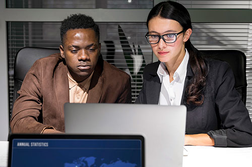 Man and woman analyzing cybersecurity on laptop